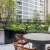 a grill next to a table and chairs with lush landscaping surrounding
