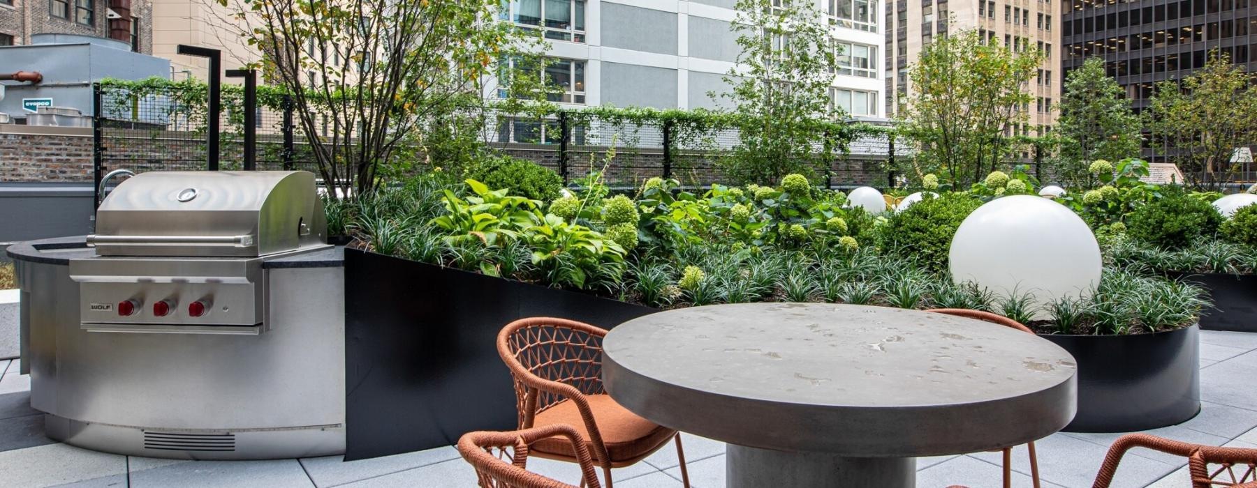 a table and chairs outside with a grill in the background